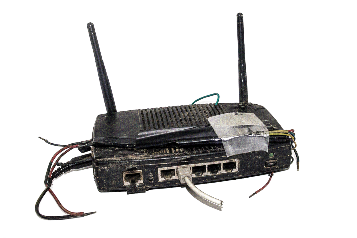 Weathered black router with exposed wires and taped casing