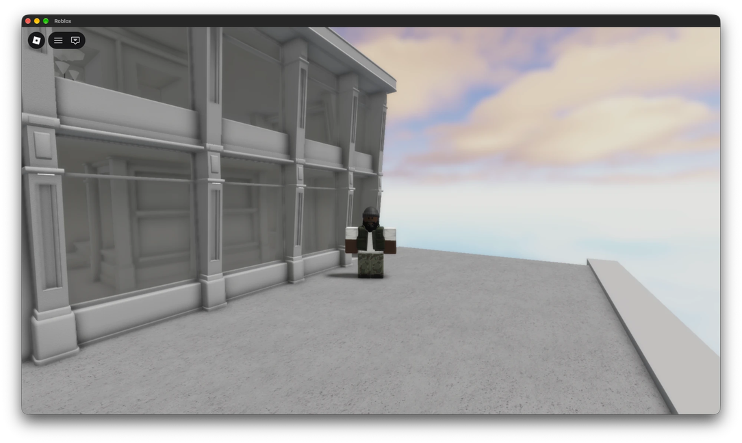 A two-storey grey facade with pilasters and balconies, a Roblox character beside it