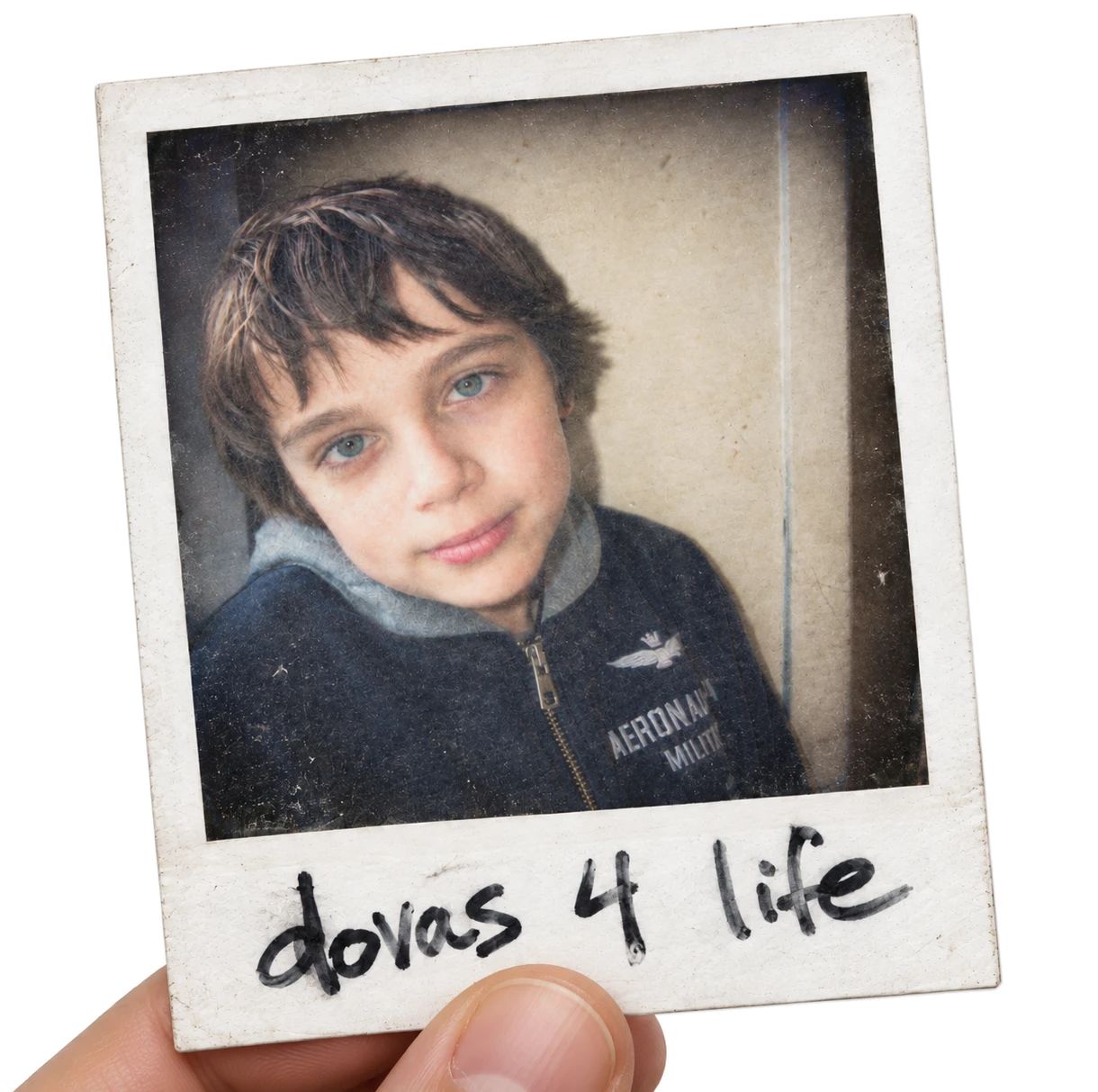 A hand holding up a polaroid of Dovas as a boy, with dovas 4 life written under it in marker