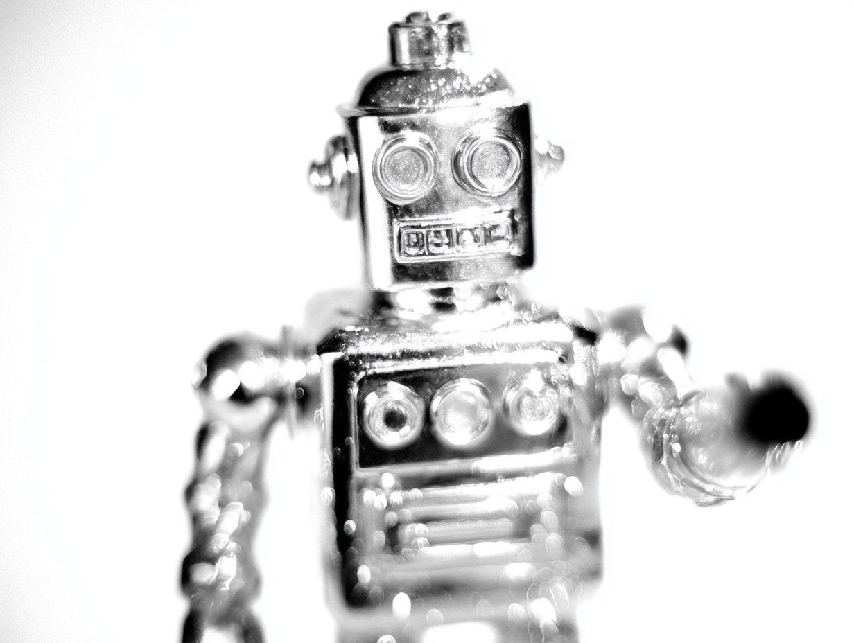 A chrome toy robot, overexposed against white